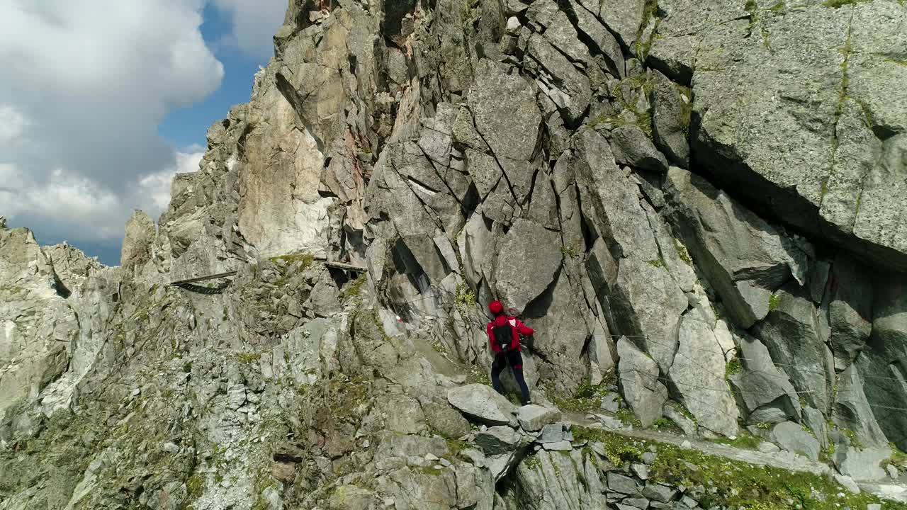 专业登山者在悬崖附近的极端山路上行走的无人机视图。高海拔山地运动的挑战路径。视频素材