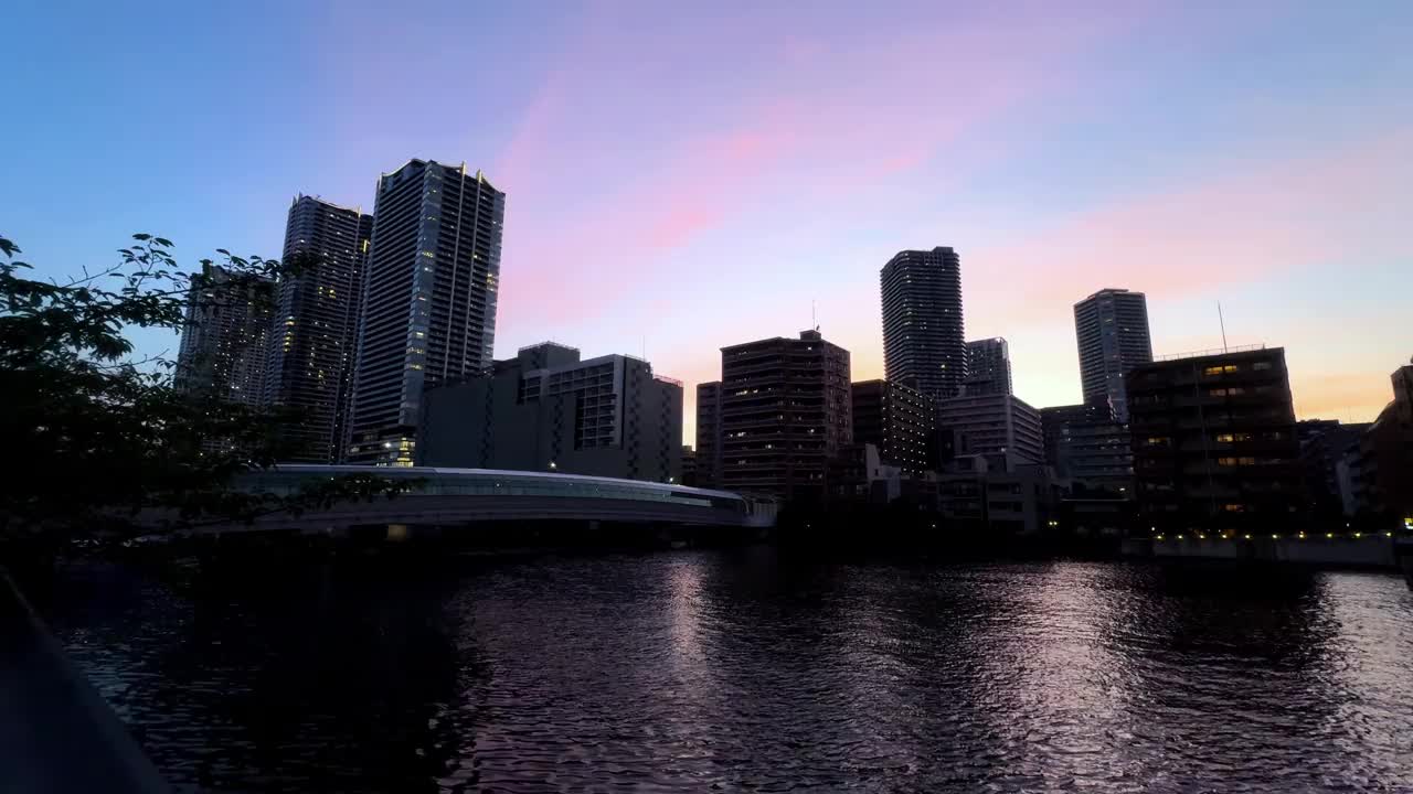 傍晚的城市天际线，五彩缤纷的夕阳映照在平静的河流上视频素材