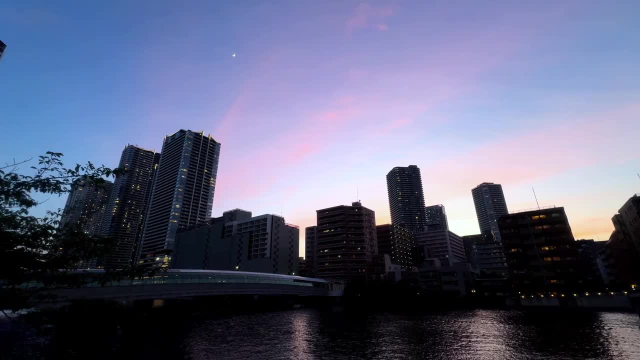 日落时分的城市天际线，五彩缤纷的天空反射在平静的河流上视频素材