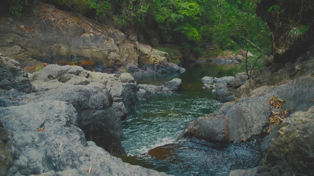 在泰国考索国家公园，风景优美的河流流经岩石地形，周围环绕着郁郁葱葱的绿色植物视频素材