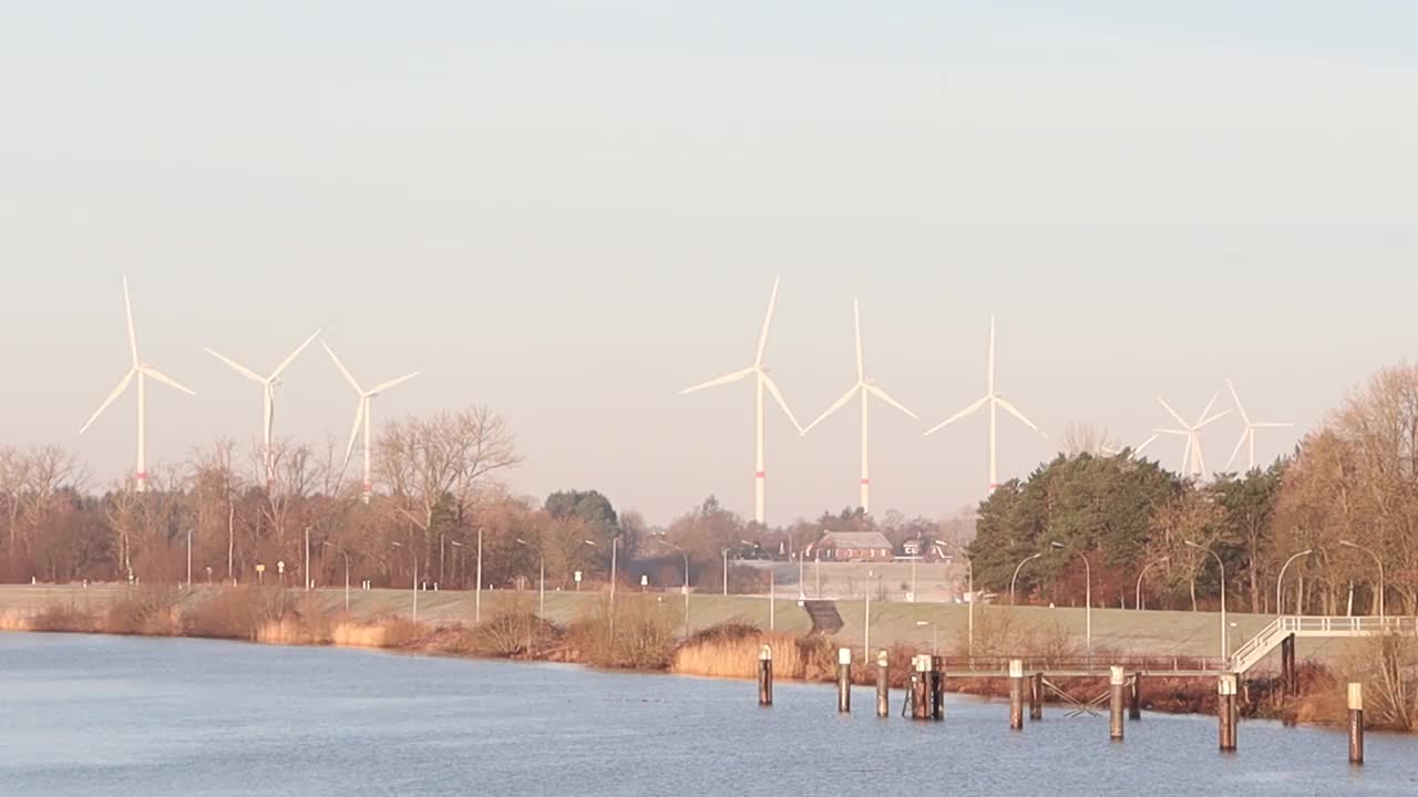 在晴朗的日子里，河流附近的风力涡轮机与风景融为一体视频素材