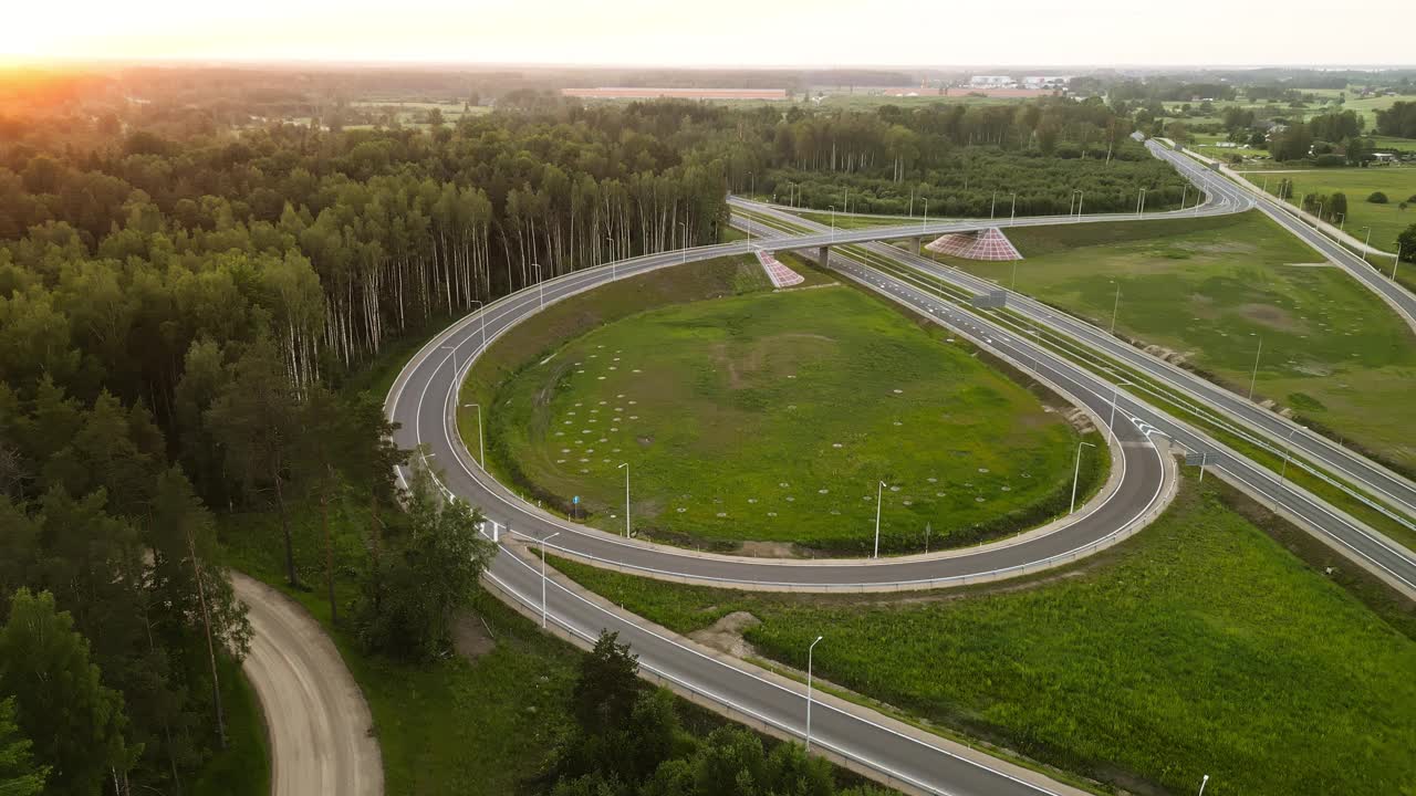 日落时绿色景观中的高速公路交叉口鸟瞰图，展示了自然和交通基础设施视频素材