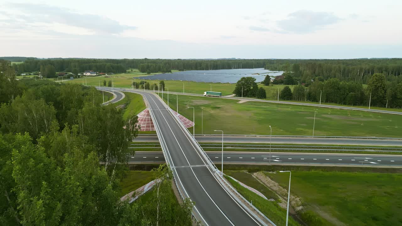 鸟瞰一条乡村公路，周围环绕着绿色的田野，一片湖泊，展现了风景的美丽视频素材