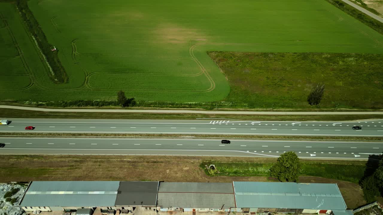 鸟瞰图:乡村公路上的汽车穿过农田，下面是绿色的田野和乡村景观视频素材