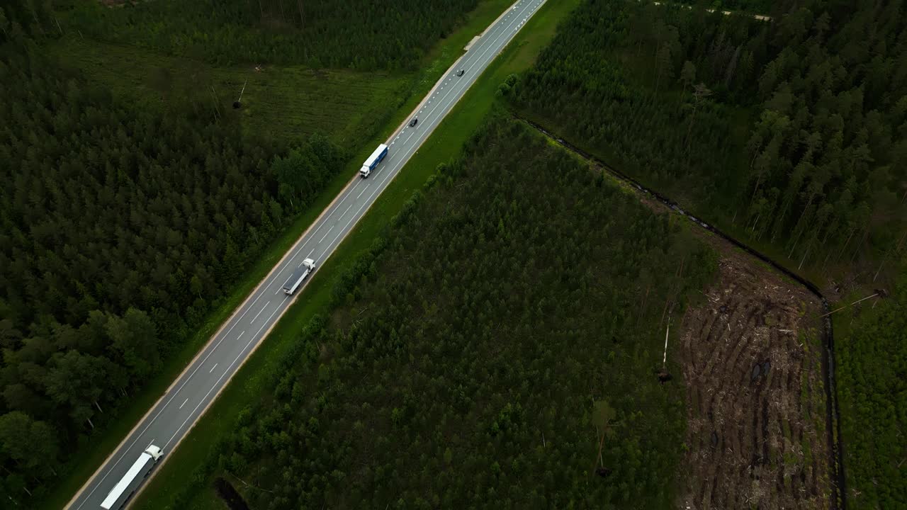 公路鸟瞰图，卡车在森林景观中行驶，展示了运输和物流的运作视频素材