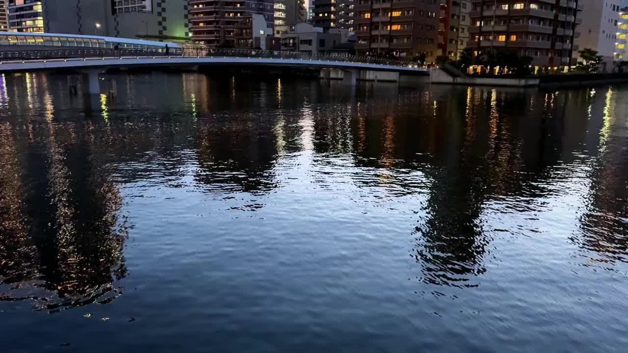 城市景观在暮色中映照在河上，建筑物被照亮视频素材