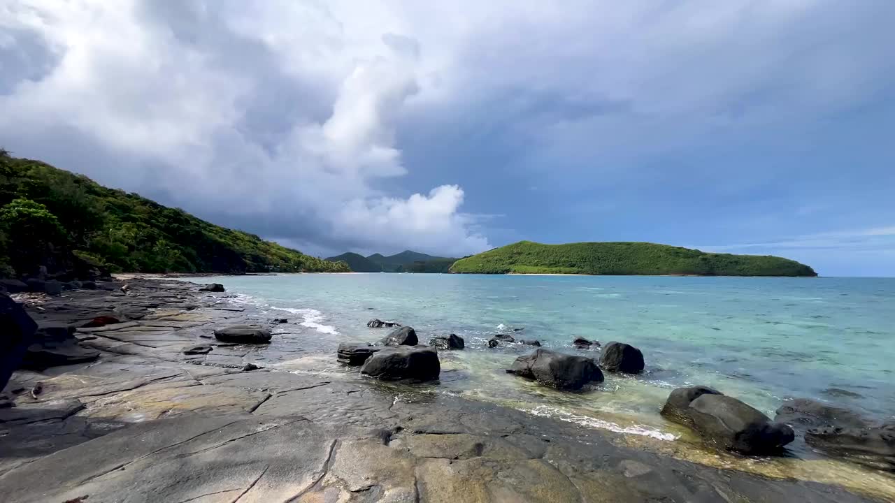 在斐济的亚泽瓦群岛曼塔雷岛度假村附近的热带海滩尽头的岩石区域，在一个蓝天的夏天视频素材