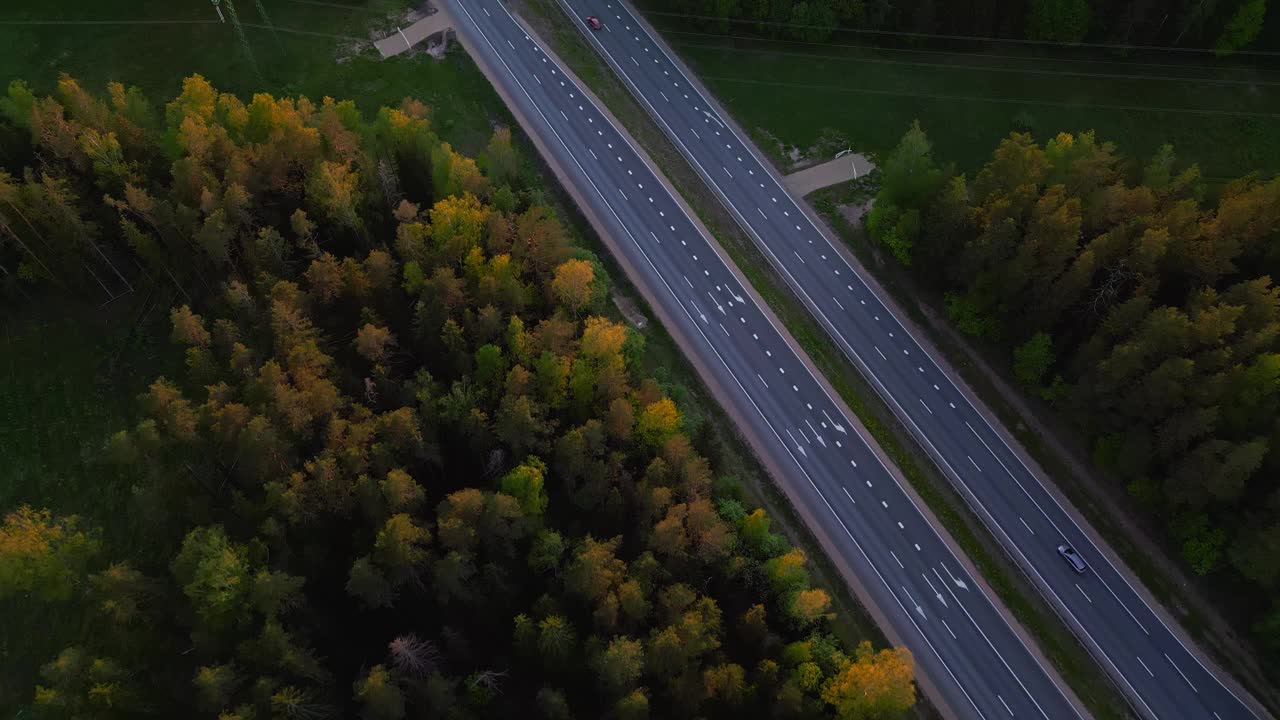 黄昏时分穿过森林的高速公路鸟瞰图，显示车辆和城市基础设施视频素材