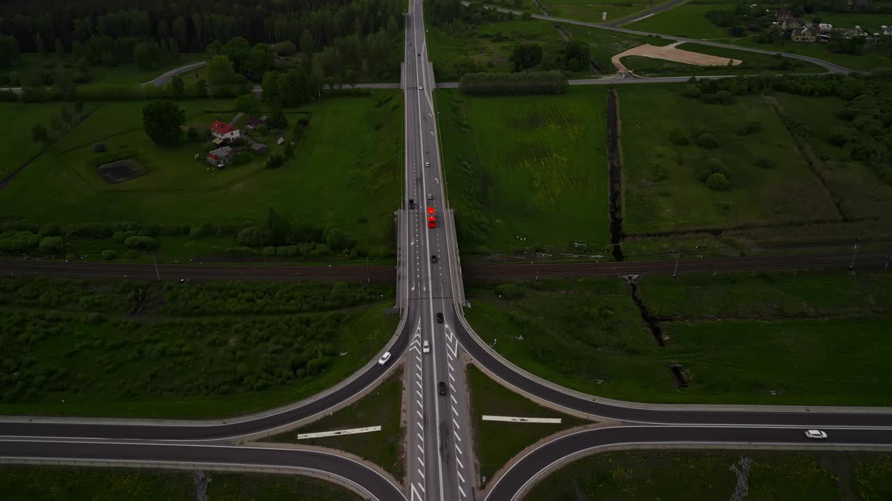 无人机拍摄的乡村公路交叉口鸟瞰图，绿色植物、行驶中的车辆和晴朗的天空视频素材