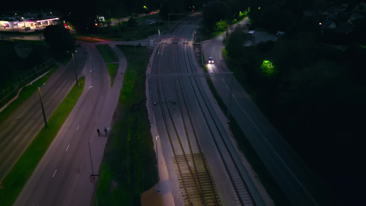 夜景鸟瞰城市街道和铁路交叉口，稀疏的交通和城市灯光照亮视频素材