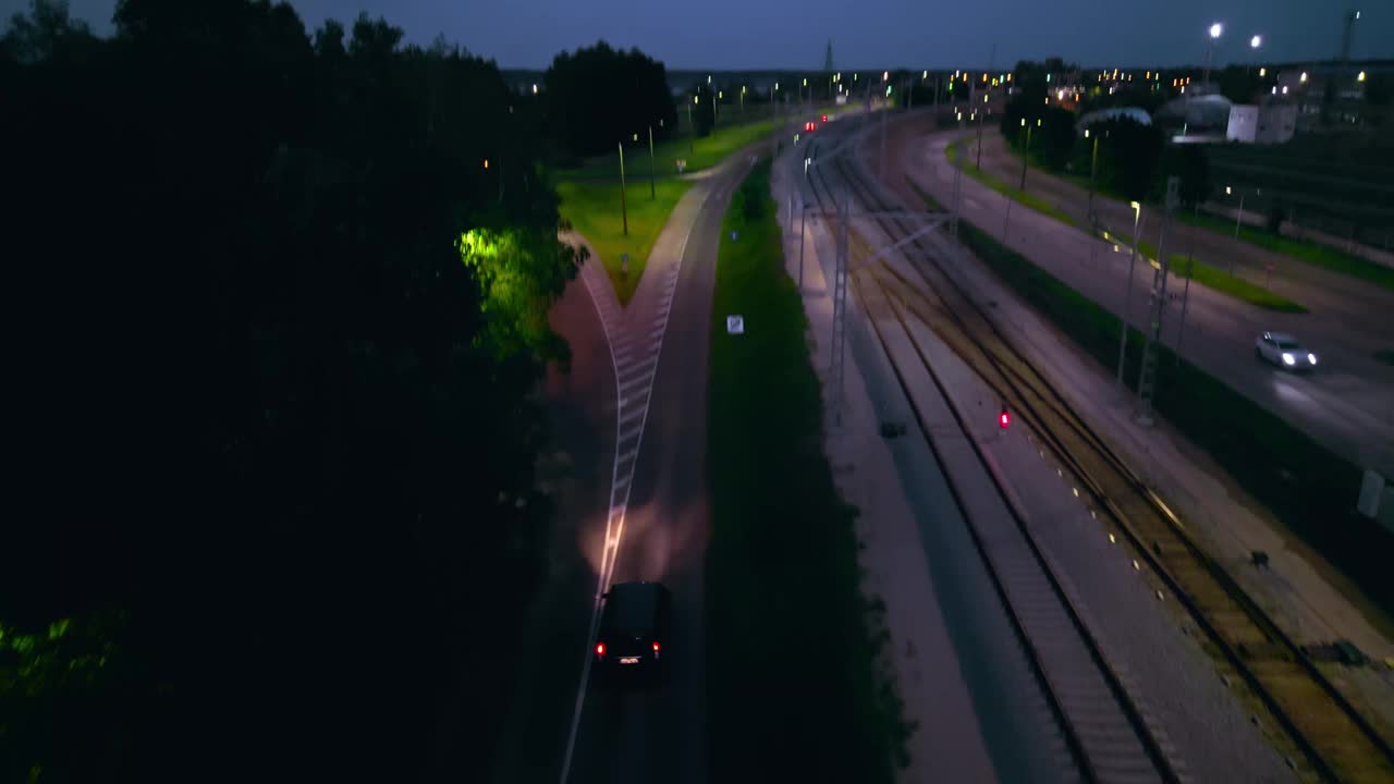 黄昏时的道路和铁路视图，显示移动的车辆，路灯和城市交通基础设施视频素材