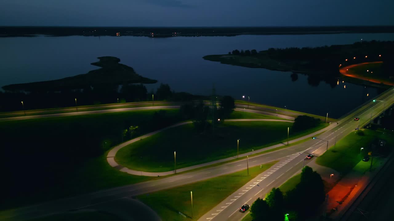 一个迷人的夜间鸟瞰湖与照明的道路，创造一个宁静和宁静的气氛视频素材