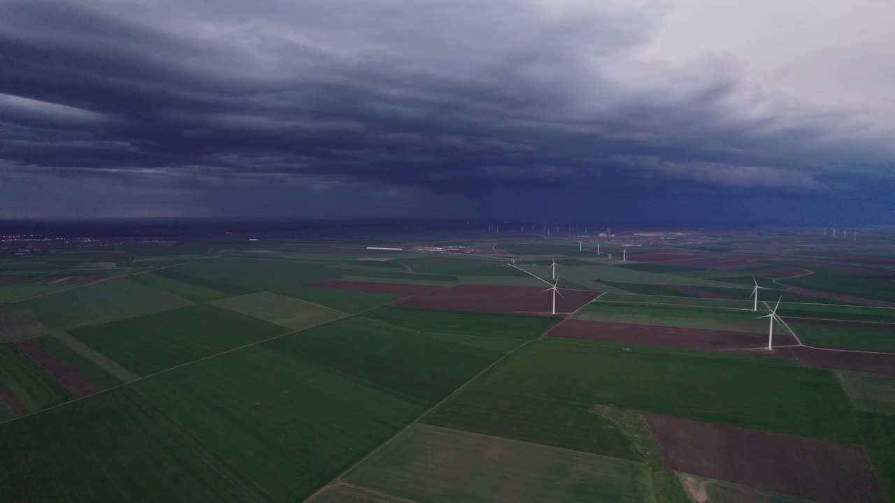 在黑暗、暴风雨的天空下，绿色田野上的风力涡轮机视频素材