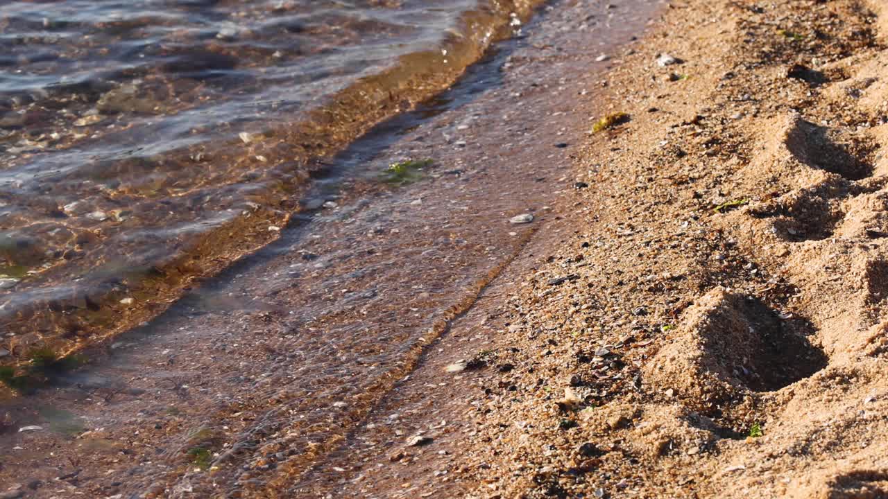 海浪冲刷着沙滩上的脚印视频素材