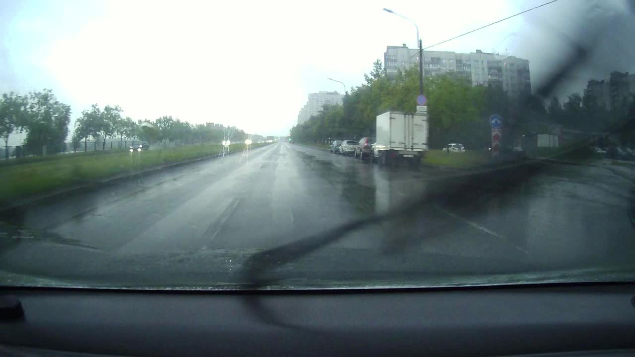 城市里下着大雨，从车上看雨刮器上的街道。汽车的雨刷在雨中猛烈地摆动着视频素材