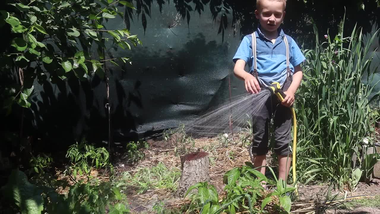 一个夏日，小农夫在花园里给植物浇水视频素材