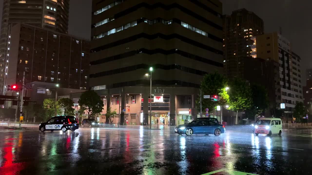 夜晚的城市十字路口，潮湿的路面和汽车反射出五颜六色的灯光视频素材