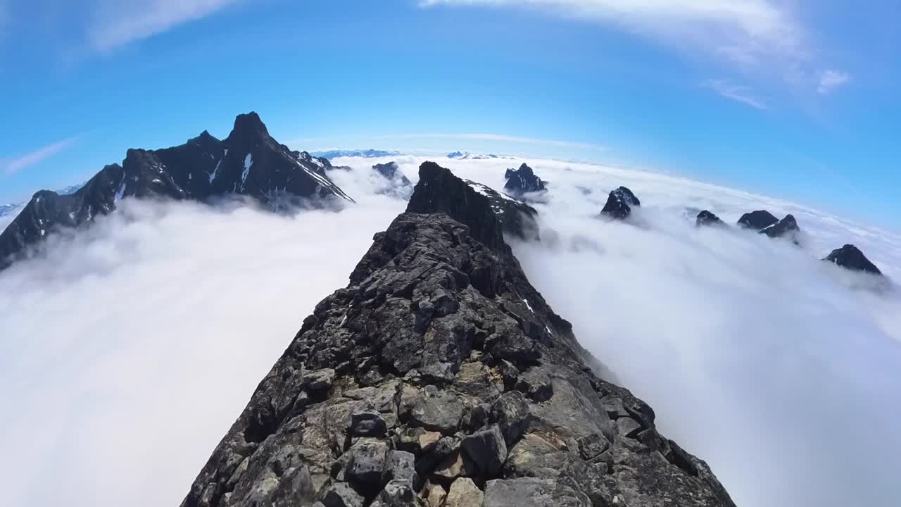 在一个晴朗的日子里，在挪威山区云层上方陡峭的山脊上进行POV登山。视频素材