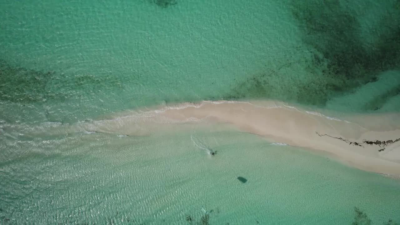 风筝冲浪者在阿瓜岛原始沙滩附近的清澈碧绿的海水上滑翔视频素材