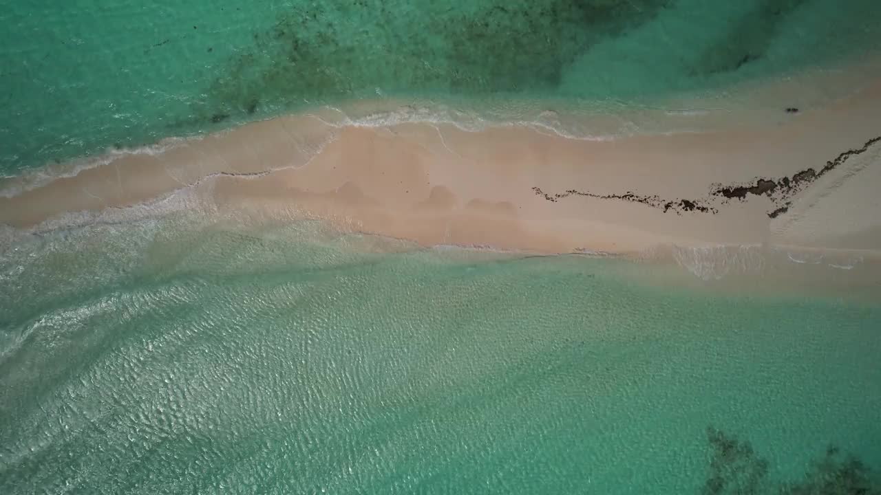 从空中俯瞰，清澈碧绿的海水中狭窄的沙带视频素材