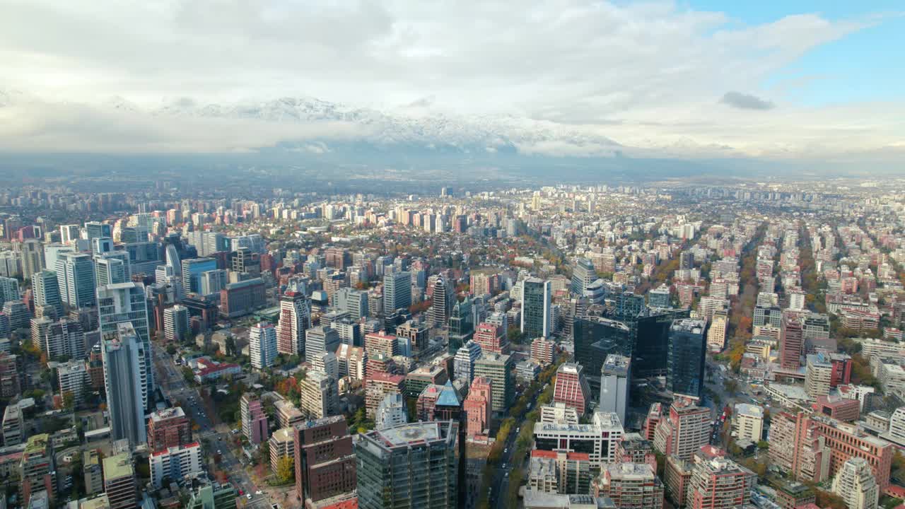 飞越智利圣地亚哥的现代建筑，安第斯山脉在一个晴朗的日子里布满了云。巨大视频素材