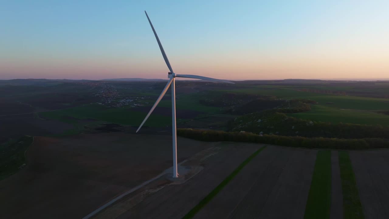 风力涡轮机在日落时分矗立在广阔的景观中，利用可再生能源视频下载