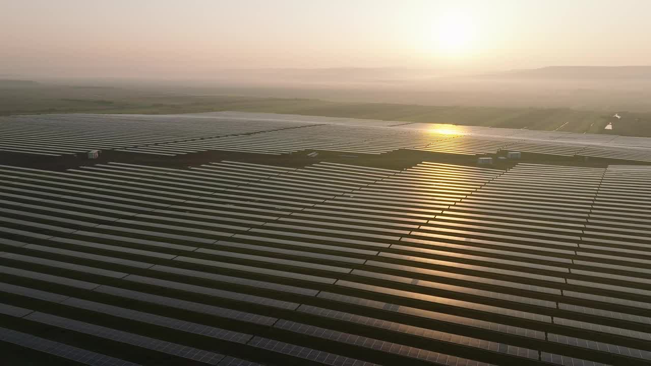 一个巨大的太阳能农场上的日出，一排排的太阳能电池板一直延伸到地平线视频下载