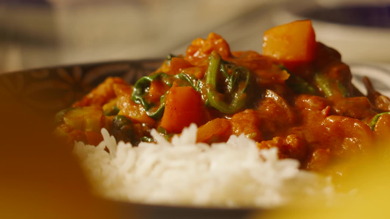 美味的印度菜蔬菜Tikka Masala咖喱花椰菜，菠菜，辣椒和传统的印度香米- 4K镜头视频下载