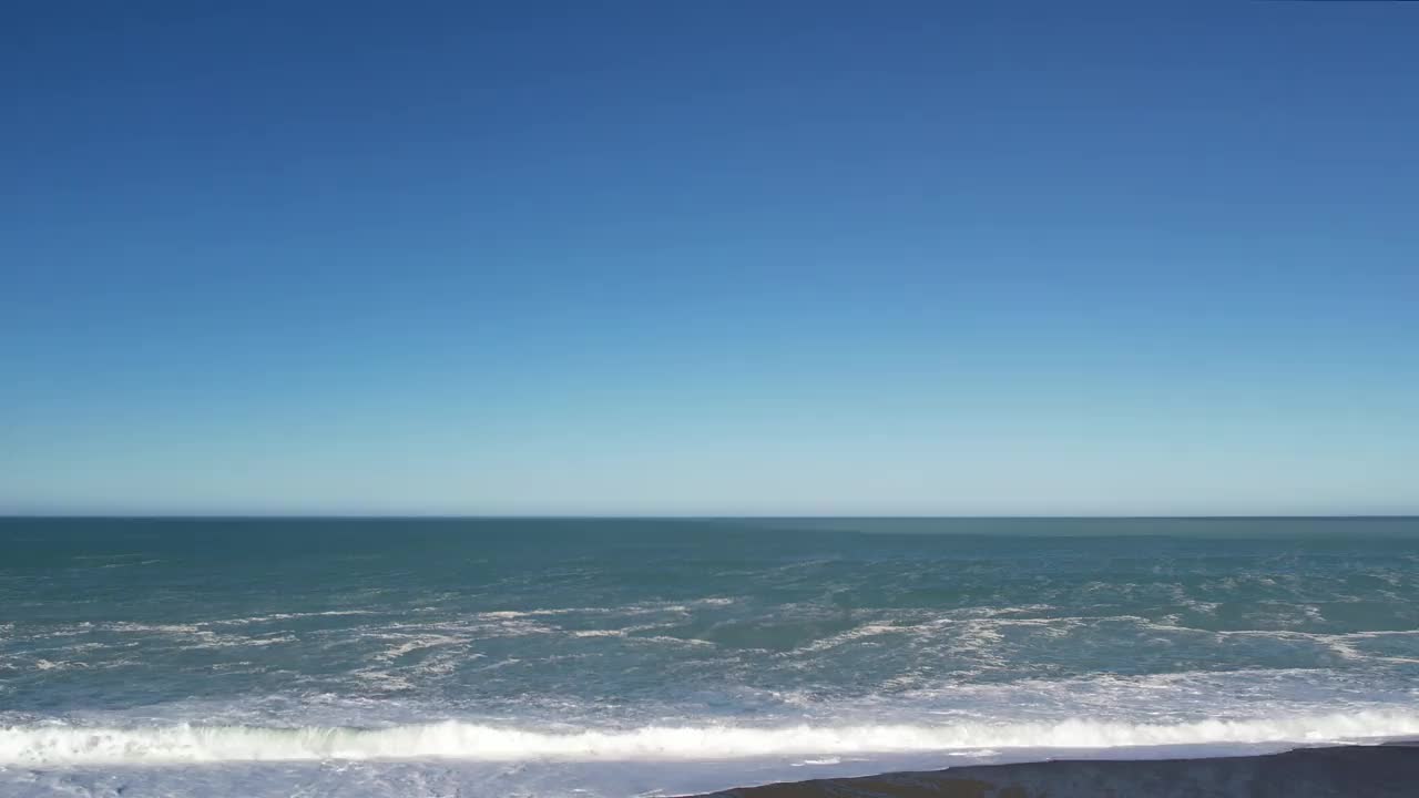缓慢和低空接近小波浪翻滚到石质海滩-鸟滩，海滩(新西兰)视频下载