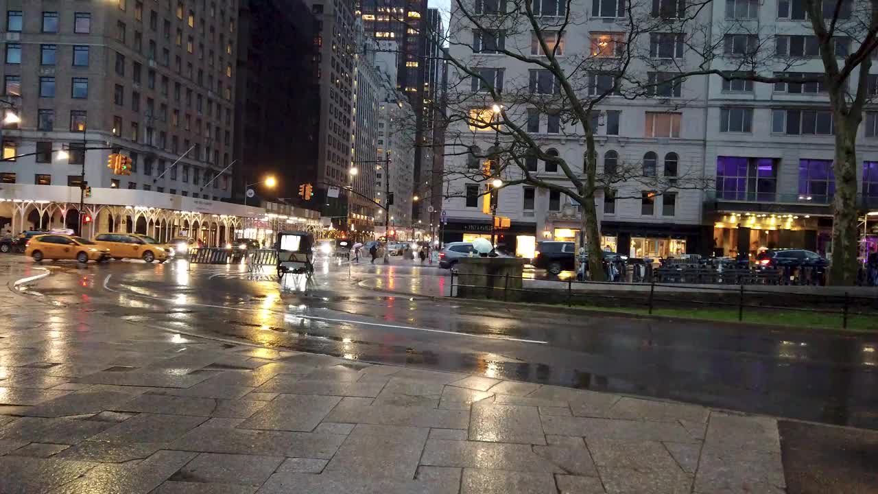 在纽约一个下雨的下午，从中央公园观察交通信号灯的十字路口拍摄的第六大道的减速镜头视频下载