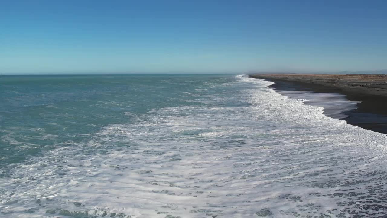 在一个晴朗、阳光明媚的日子里，从美丽的绿松石般的海洋中缓缓飞过的白浪——鸟雀滩，海滩(新西兰)视频下载