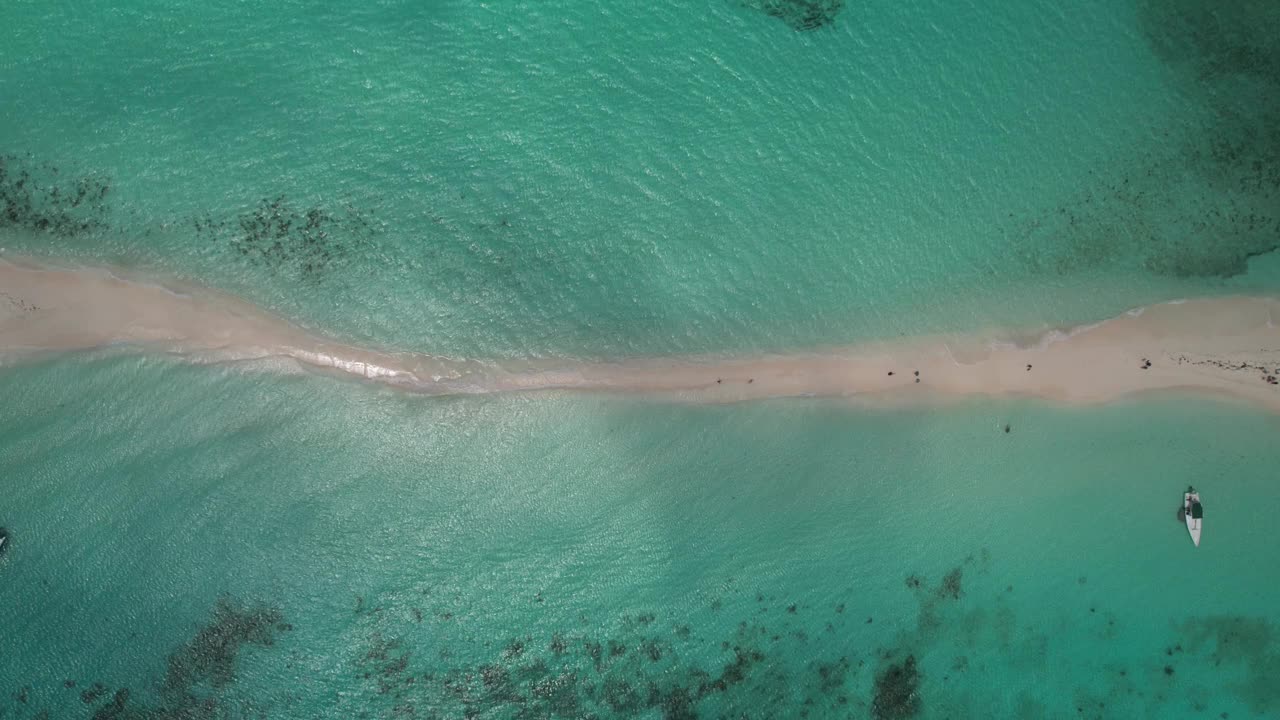 碧绿的海水中有一个细细的沙洲，人们在散步，附近有一艘皮艇，鸟瞰图，时间流逝视频素材