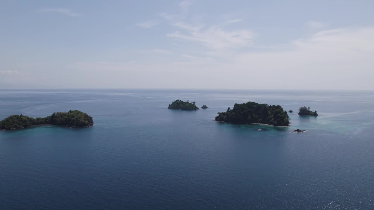 阳光明媚的日子里，郁郁葱葱的热带岛屿在清澈的蓝色海洋中鸟瞰图视频素材