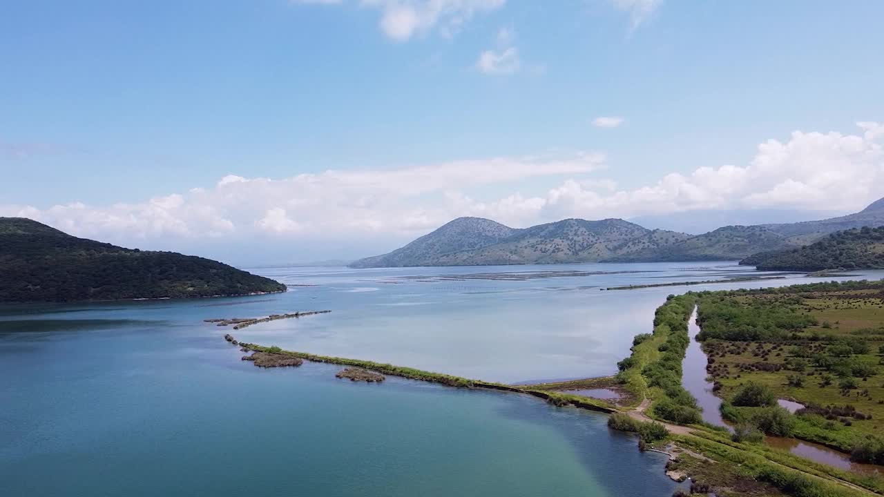 在布特林特国家考古公园附近的宁静阿尔巴尼亚景观鸟瞰图，拥有平静的蓝色海水，郁郁葱葱的绿色植物，和遥远的山脉。视频素材