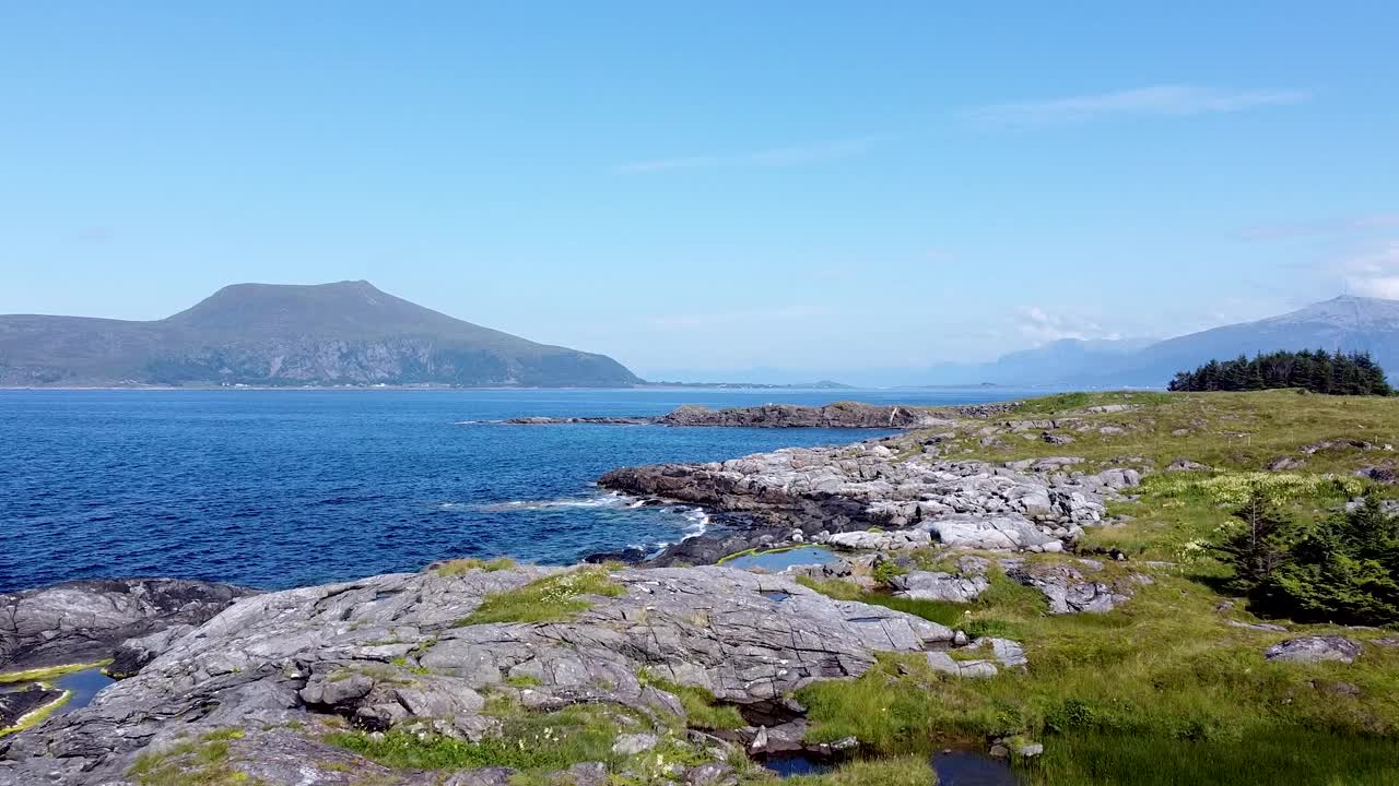 鸟瞰挪威Møre og Romsdal崎岖的海岸线，拥有清澈的蓝色海水，岩石海岸和遥远的山脉。视频素材