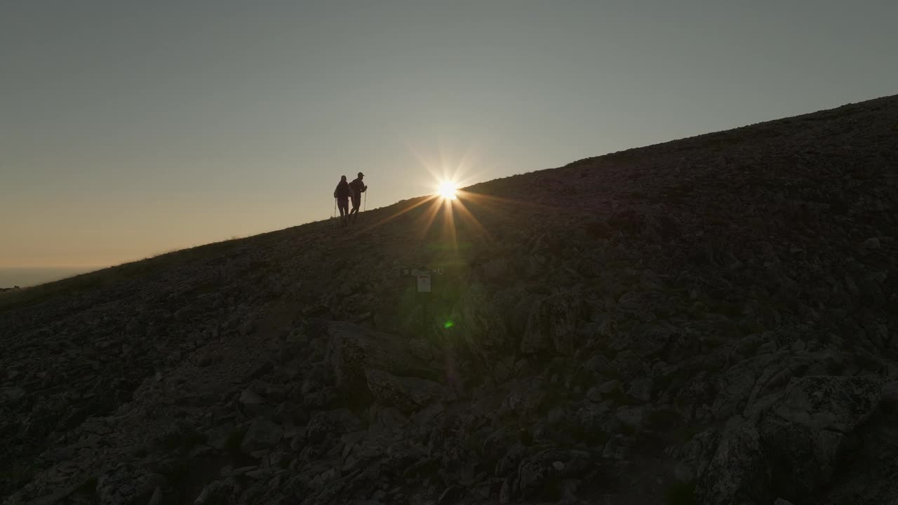 一对年轻的夫妇在挪威森加的Husfjellet徒步旅行，在一个令人惊叹的午夜日落视频素材