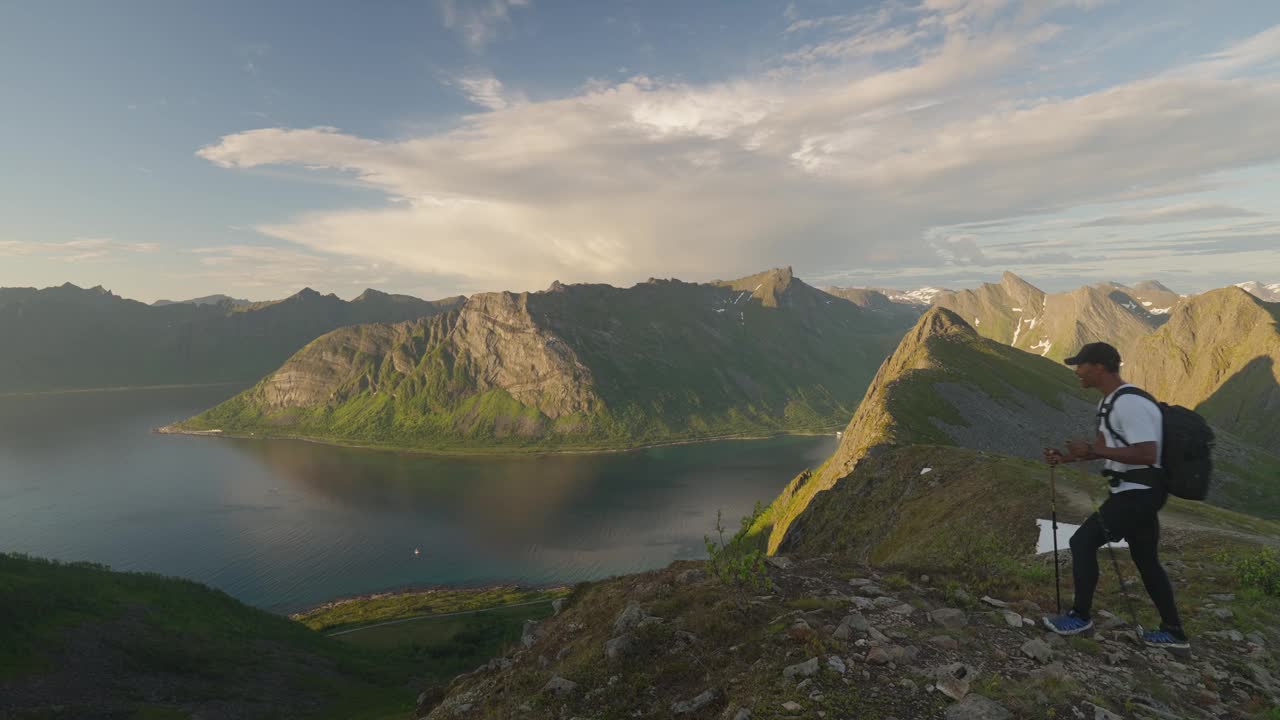 一对年轻夫妇在日落时分在挪威的Senja Husfjellet山上徒步旅行，欣赏峡湾的壮丽景色视频素材