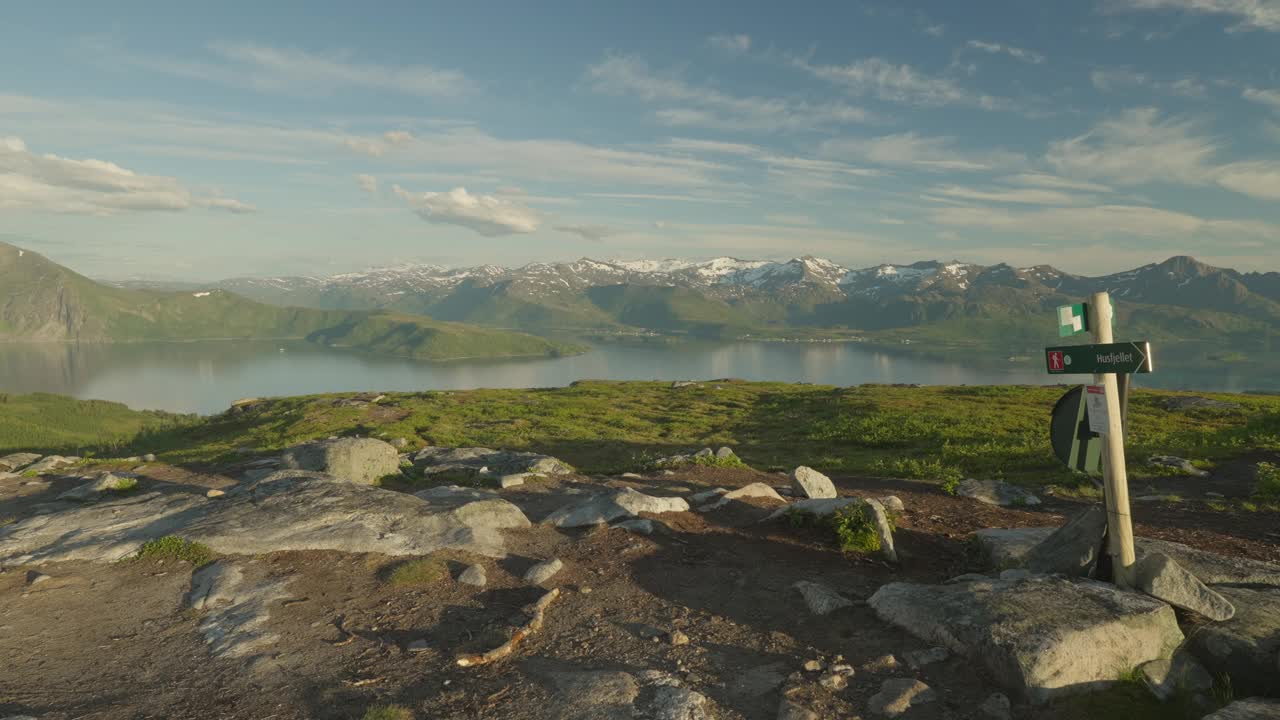 一对年轻夫妇在挪威的Senja Husfjellet徒步旅行，背景是白雪覆盖的山峰视频素材