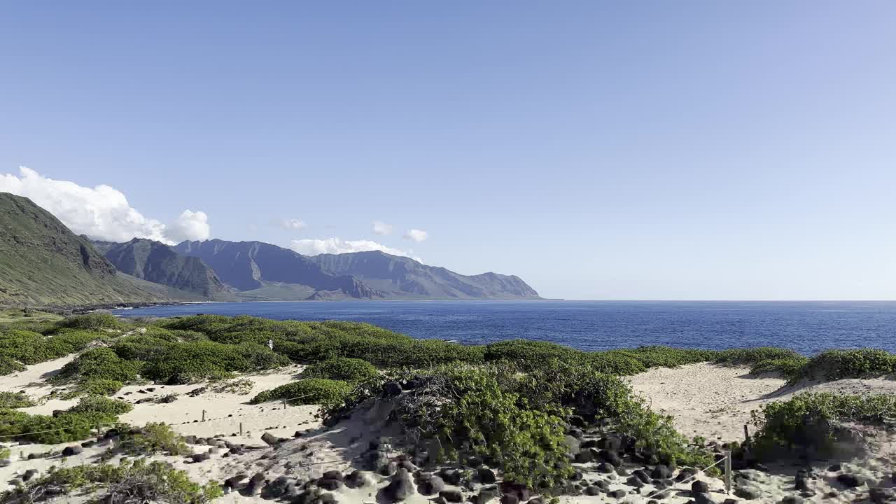 在夏威夷的瓦胡岛，您可以欣赏到雄伟的山脉和郁郁葱葱的海岸线
沙丘、绿色植被和湛蓝天空下广阔的太平洋，凸显了岛上多样的自然美景。视频素材