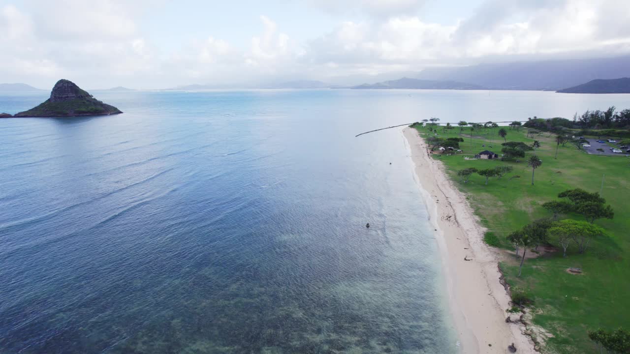 广阔的鸟瞰图展示了瓦胡岛宁静的海岸线，清澈的蓝色海水，郁郁葱葱的绿色植物，以及远处标志性的Mokoli'i岛。完美的热带天堂。视频素材