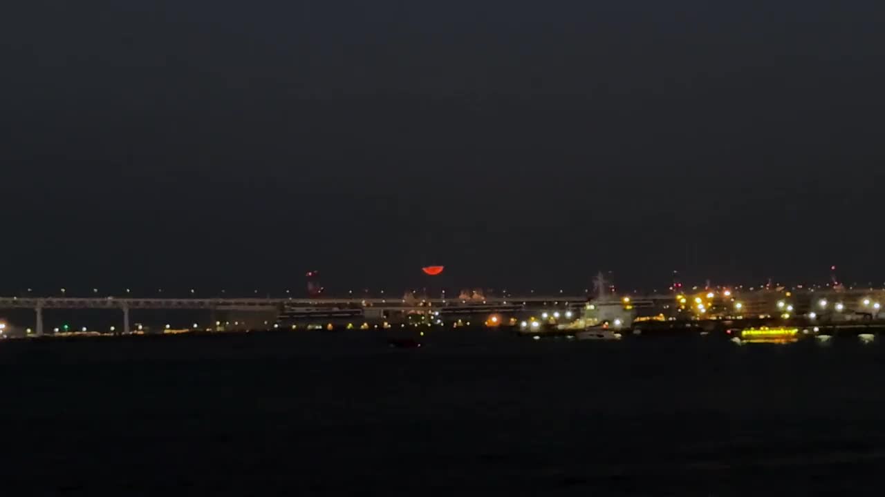 夜晚的桥梁和城市景观，背景是一轮冉冉升起的红月视频素材