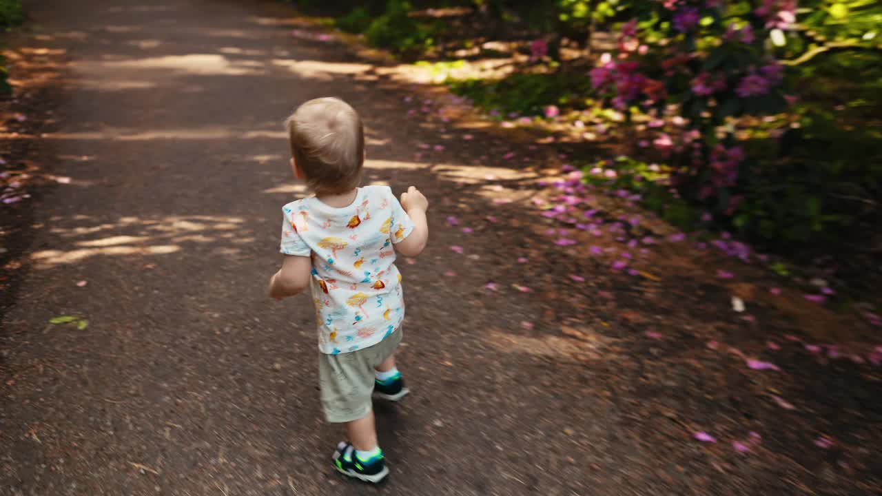 一个年幼的孩子走在阳光明媚的小路上，被大自然包围，高分辨率4K质量拍摄视频素材