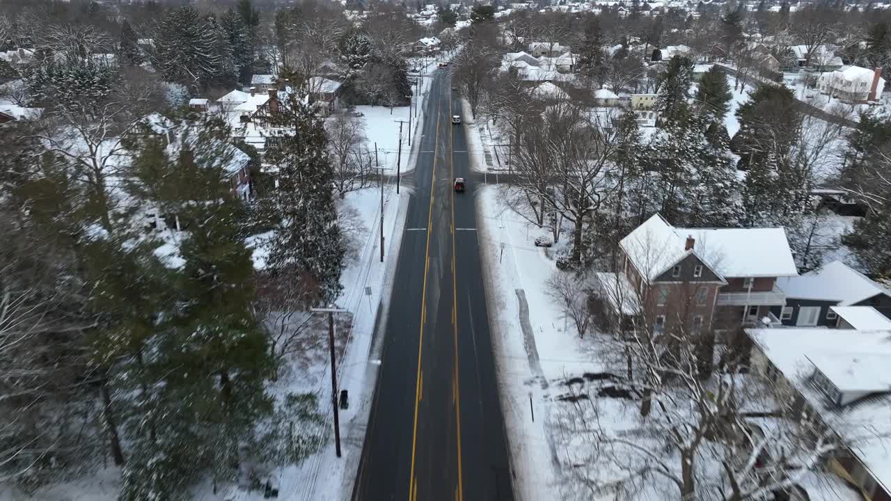 航空跟踪拍摄的汽车在积雪的冬季道路上的美国社区。白雪覆盖的景观与城镇。鸟瞰镜头。视频素材