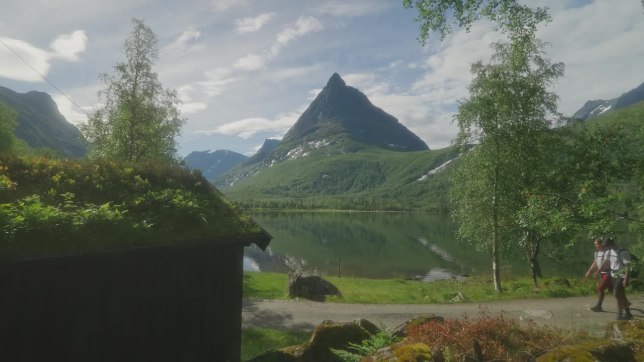 一对年轻夫妇在挪威因纳德达伦的一个风景秀丽的湖边徒步旅行，背后是山脉视频素材