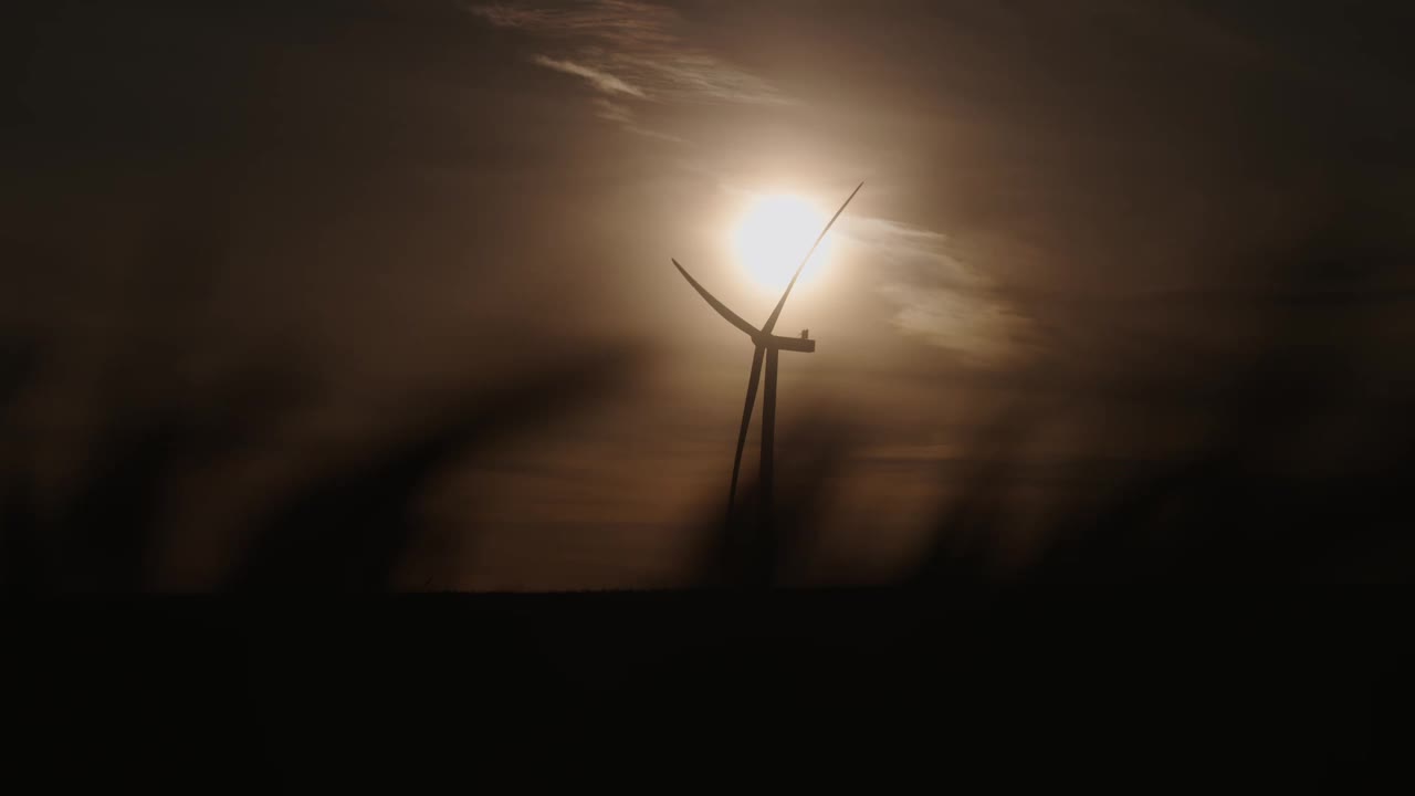 在黄昏的天空中，风力涡轮机的剪影映衬着夕阳视频素材