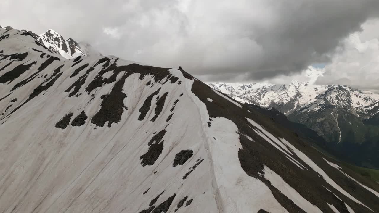 斯瓦涅季山脉的鸟瞰图，山顶被雪覆盖，天空多云。地形崎岖，海拔高，景观雄伟。冬季环境优美。山，雪，云和岩石。无人机视频素材