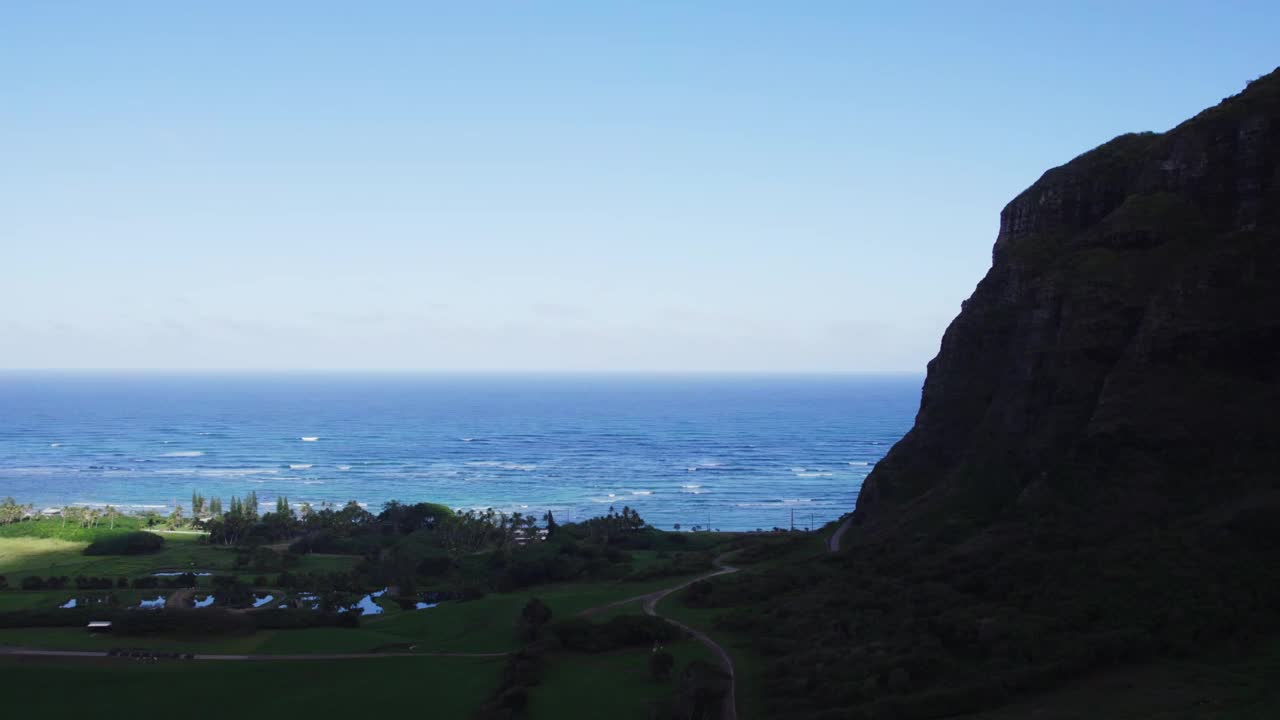 瓦胡岛海岸线令人惊叹的鸟瞰图，郁郁葱葱的绿色景观与充满活力的蓝色海洋融为一体。雄伟的悬崖构成了景色，展示了岛上的自然美景。视频素材