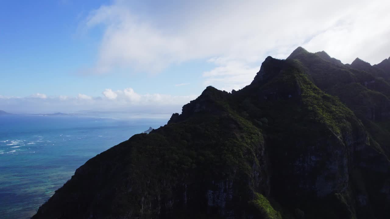 一个迷人的航拍剪辑突出雄伟的山脉和瓦胡岛清澈的海洋，夏威夷，提供了一个惊人的观点，岛上的原始自然美景。视频素材