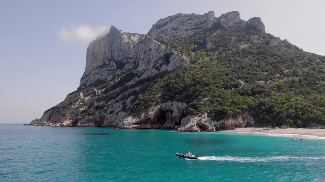 航拍图片，位于萨丁尼亚岛鲍尼海岸奥罗塞湾的旅游目的地Cala Sisine海滩上的船视频素材