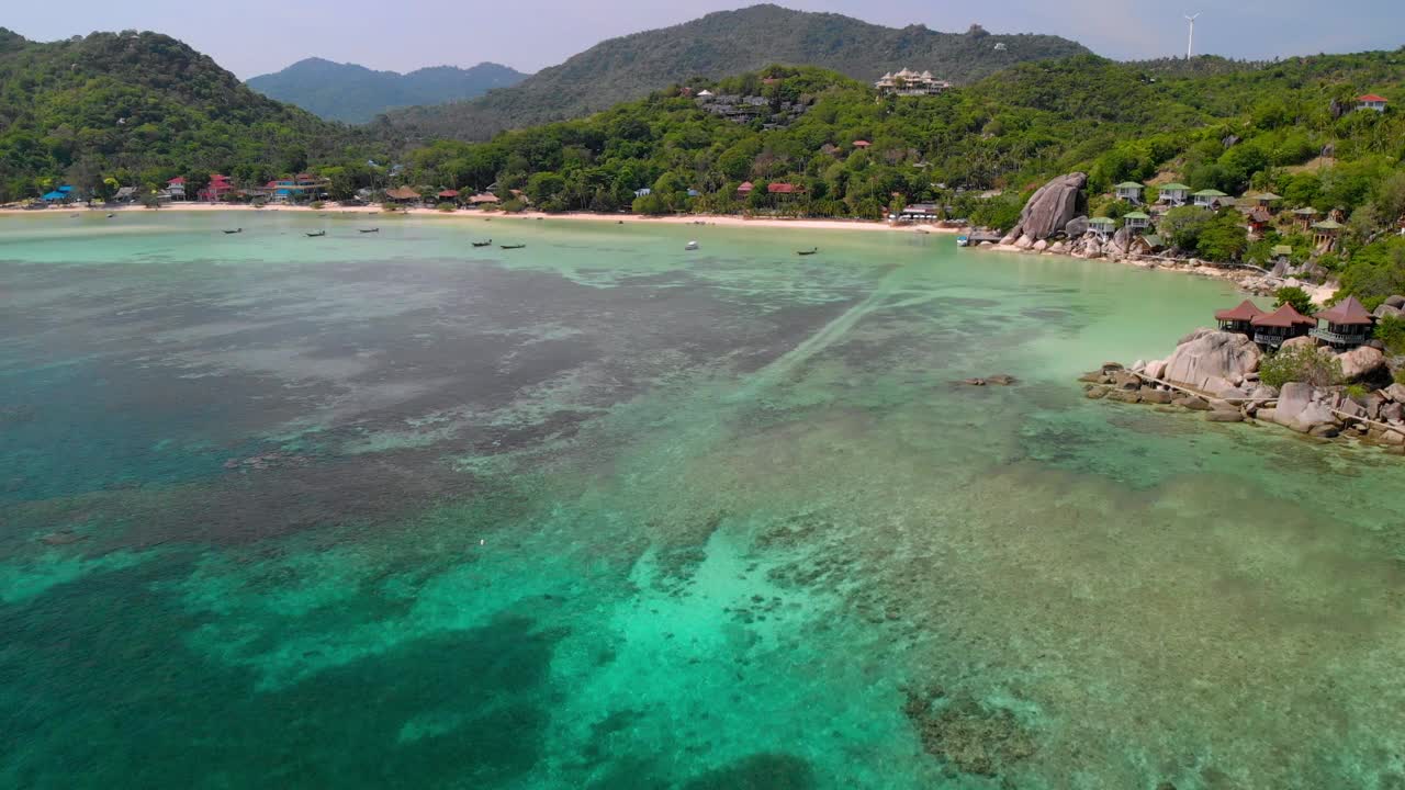 鸟瞰涛岛翠绿的海滩，岸边有山和森林。视频素材